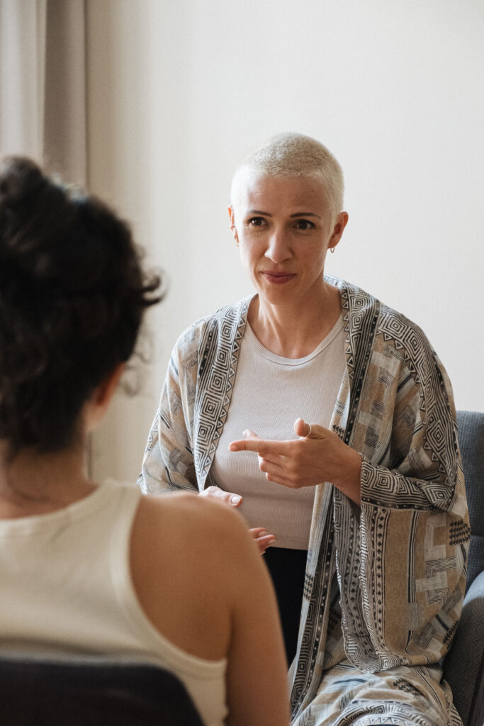 Frau mit kurzem Haar und gemustertem Kimono spricht mit einer anderen Frau