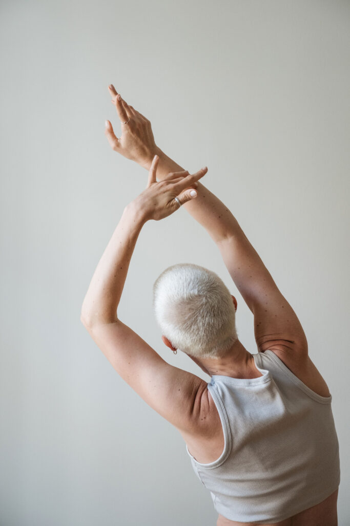 Female Yoga und Selbstliebe – Frau mit kurzen Haaren dehnt Arme achtsam zur Seite